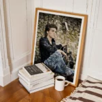 Framed photo mosaic portrait of a young man sitting with his guitar, displayed beside a stack of books and a cup of coffee.
